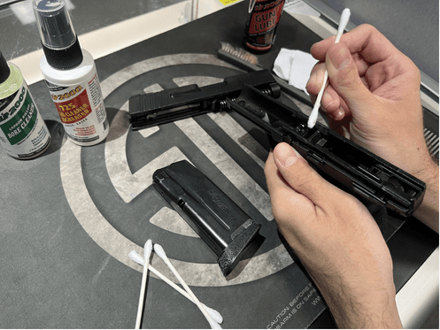 A disassembled Sig Sauer P365 firearm is being cleaned using Slip 2000 supplies